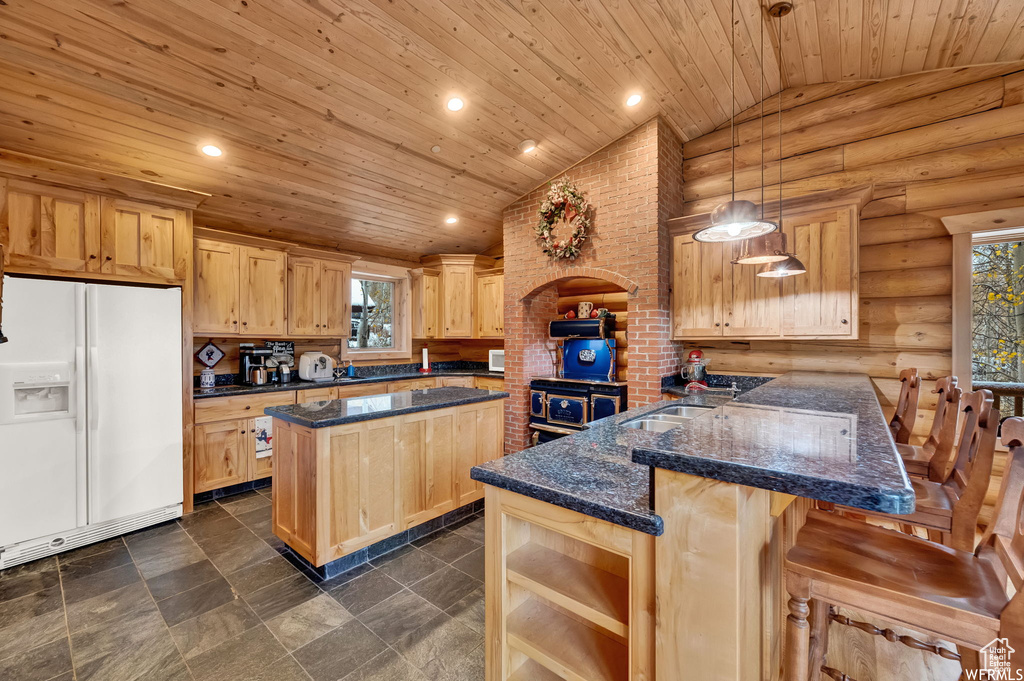 Kitchen featuring log walls, white fridge with ice dispenser, lofted ceiling, brick wall, and a kitchen breakfast bar