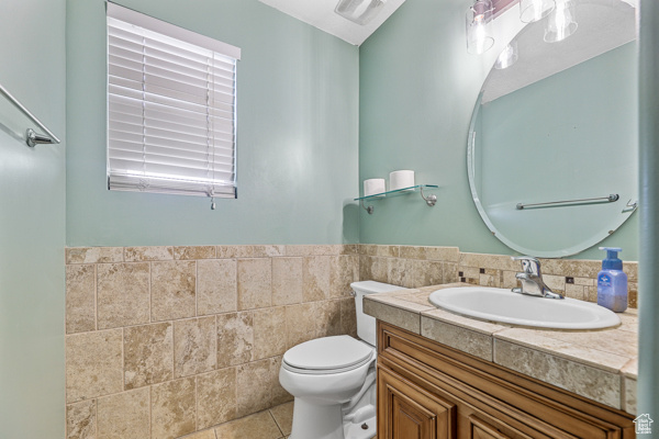 Bathroom featuring tile flooring, tile walls, large vanity, tasteful backsplash, and toilet