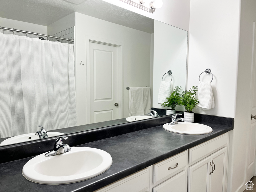 Bathroom featuring double sink, large vanity, and a textured ceiling