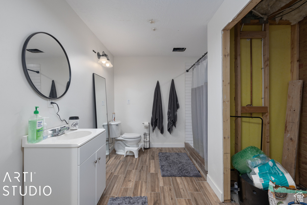 Bathroom with wood-type flooring, oversized vanity, and toilet