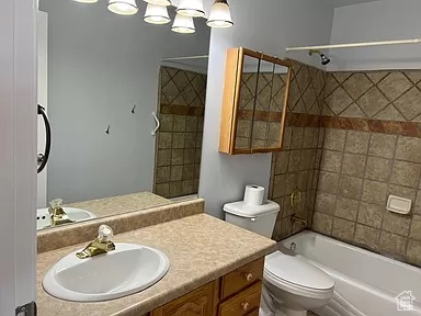 Full bathroom featuring tiled shower / bath, toilet, and large vanity