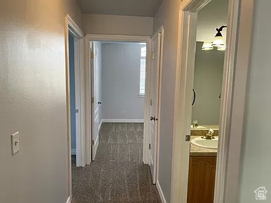 Hall with sink and dark carpet