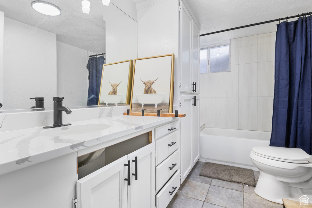 Full bathroom featuring shower / bath combination with curtain, toilet, a textured ceiling, vanity, and tile floors