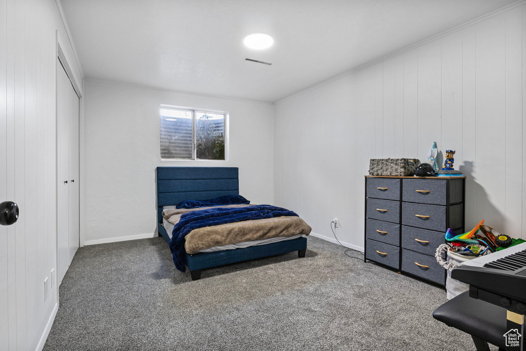 Bedroom featuring ornamental molding, a closet, and dark carpet