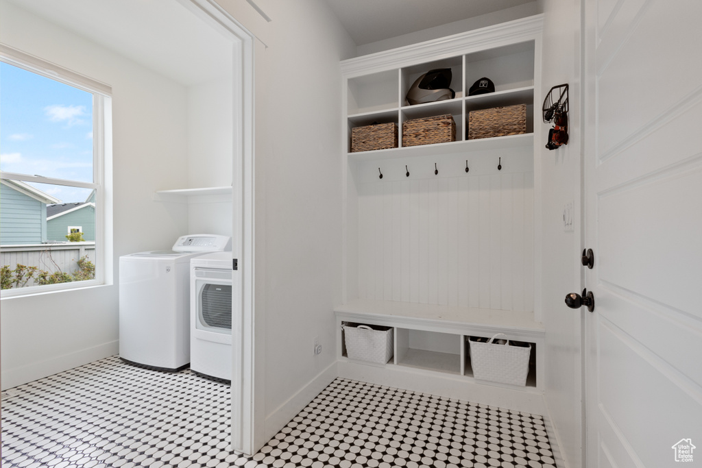 Mudroom featuring light tile flooring, a wealth of natural light, and washing machine and clothes dryer
