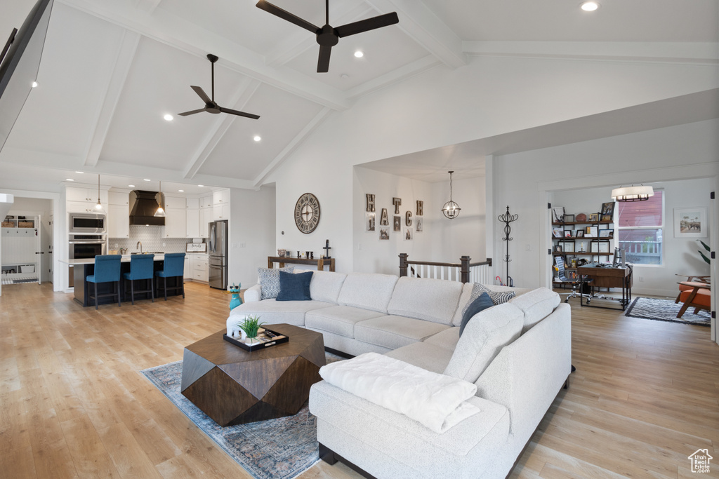 Living room with high vaulted ceiling, ceiling fan, light hardwood / wood-style floors, beamed ceiling, and sink