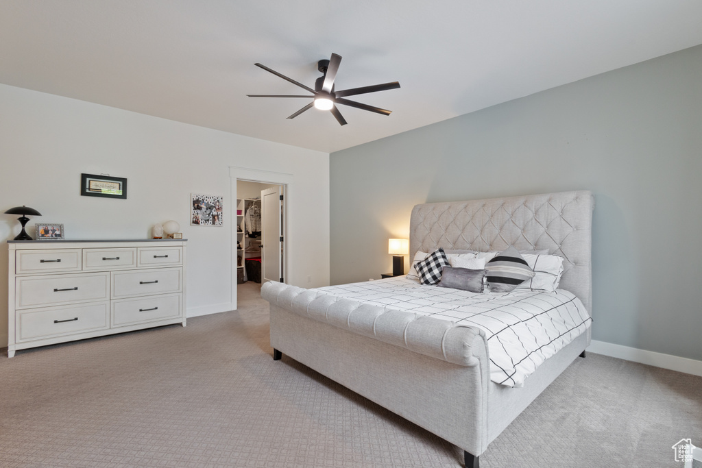 Carpeted bedroom featuring a spacious closet and ceiling fan