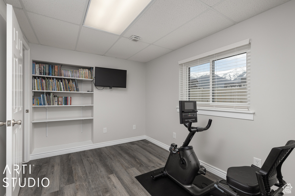 Workout room featuring a drop ceiling and dark wood-type flooring