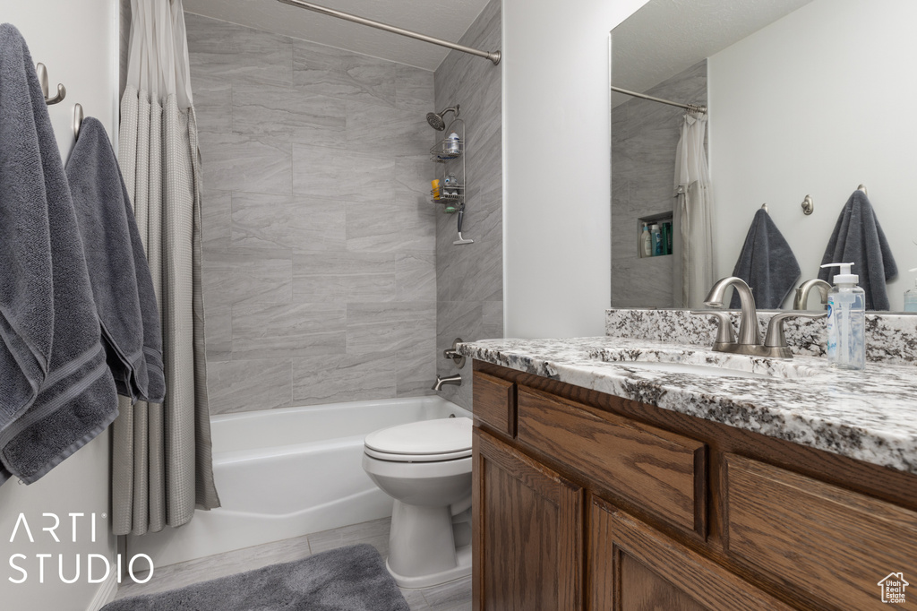 Full bathroom featuring vanity with extensive cabinet space, shower / tub combo, toilet, and tile floors
