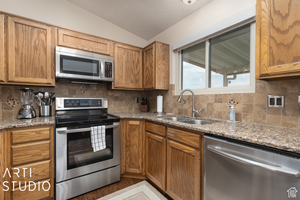 Kitchen featuring sink, backsplash, hardwood / wood-style flooring, and stainless steel appliances