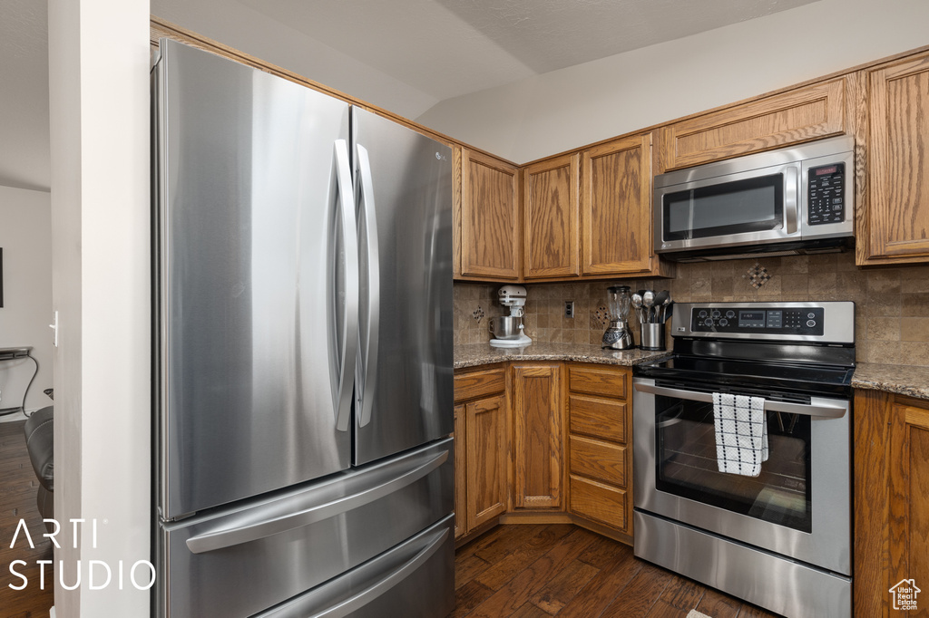 Kitchen featuring backsplash, dark hardwood / wood-style floors, stainless steel appliances, and stone countertops
