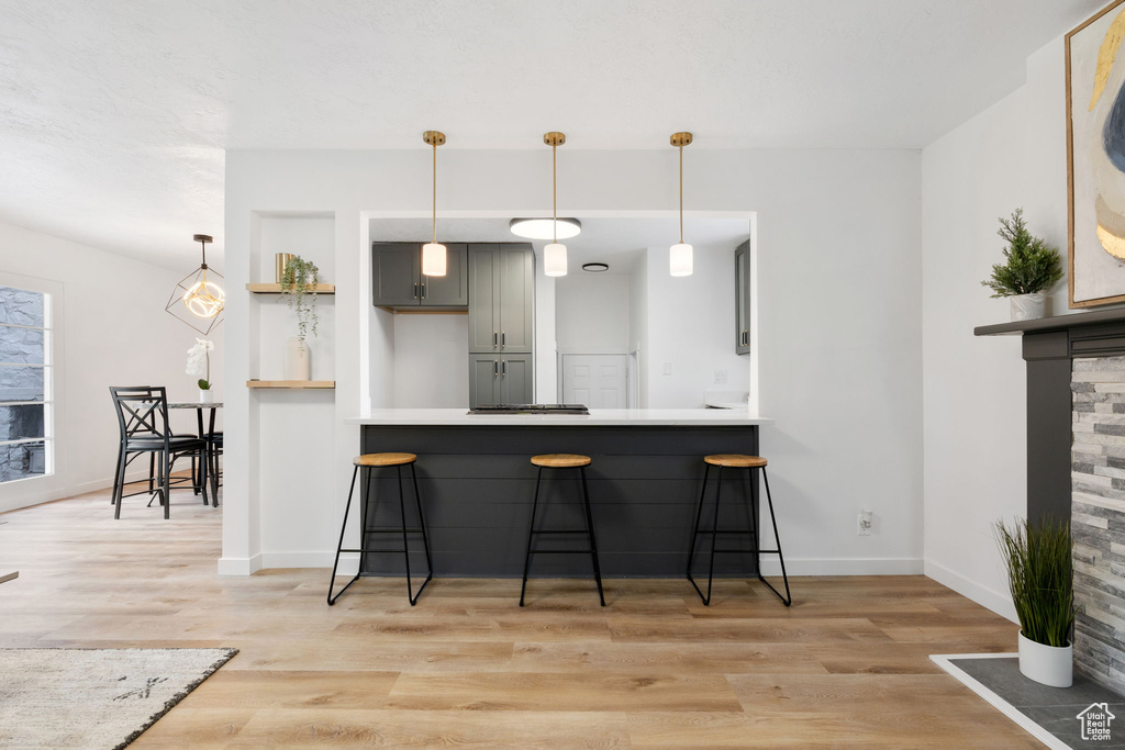 Kitchen featuring gray cabinets, a kitchen breakfast bar, light hardwood / wood-style floors, and kitchen peninsula