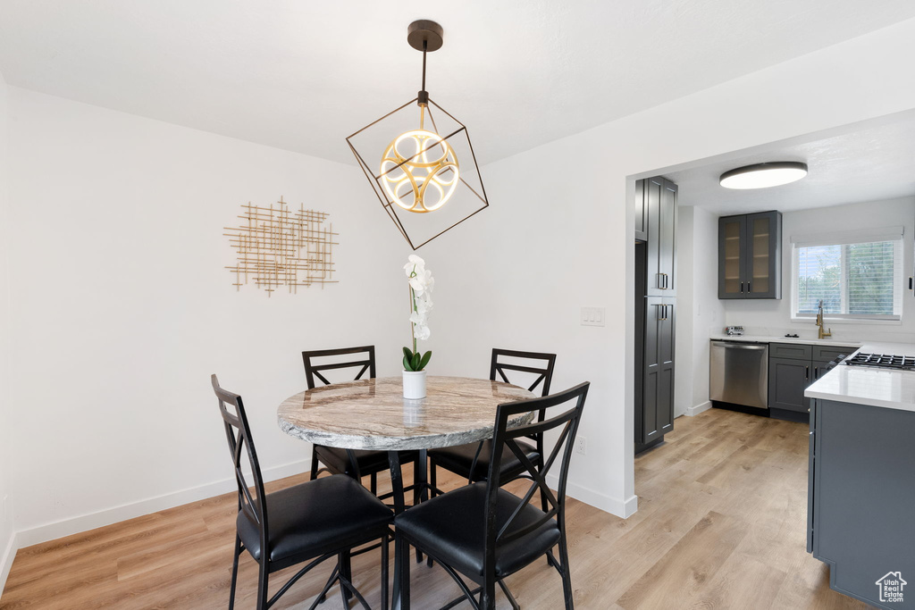 Dining space with light hardwood / wood-style flooring and an inviting chandelier