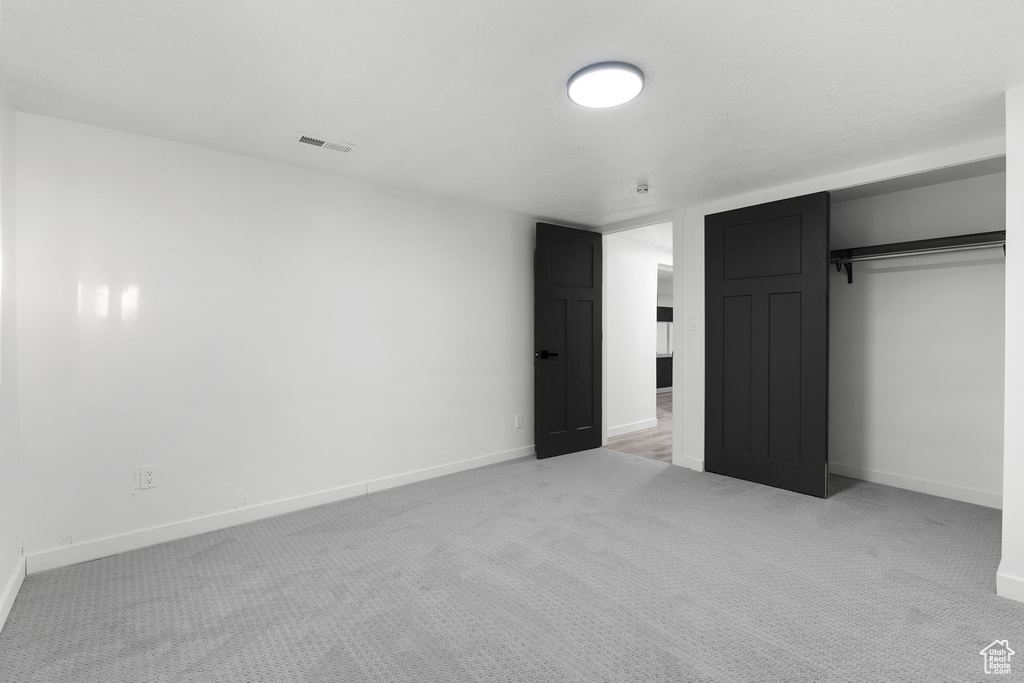 Unfurnished bedroom with light colored carpet and a closet