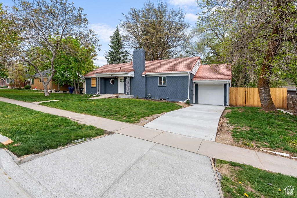 View of front facade featuring a garage and a front lawn