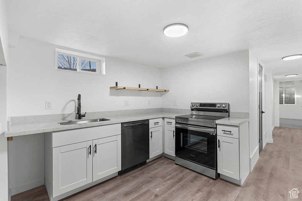 Kitchen featuring light hardwood / wood-style flooring, white cabinetry, sink, range with electric cooktop, and dishwasher