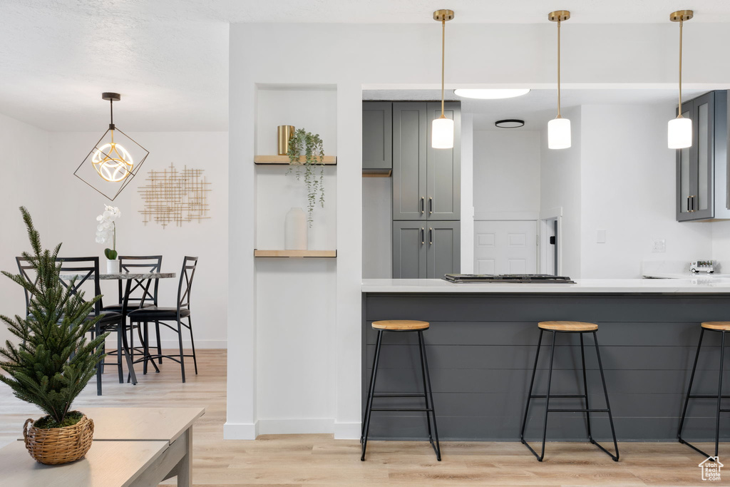 Kitchen with hanging light fixtures, light hardwood / wood-style flooring, and gray cabinets