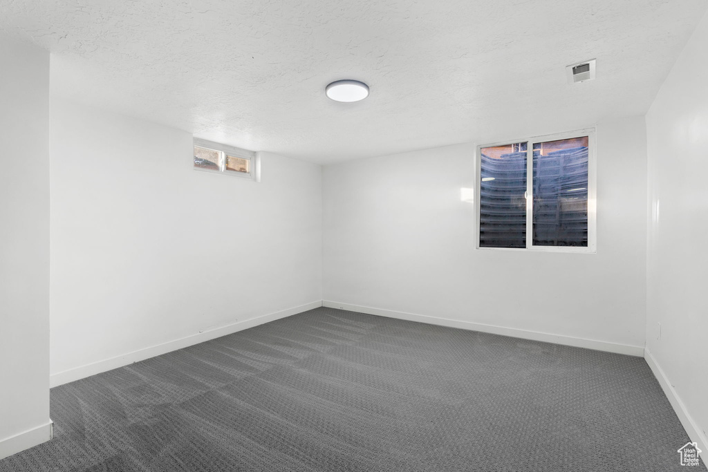 Empty room with a textured ceiling and dark carpet