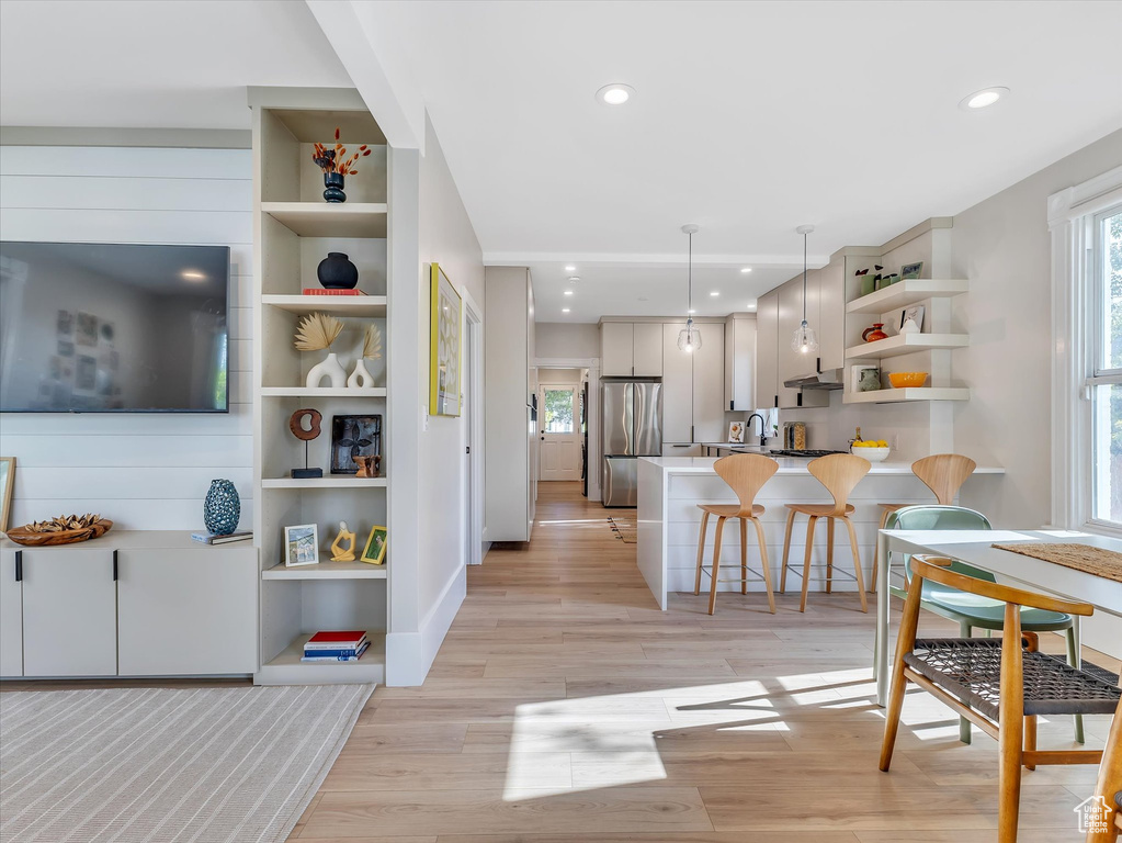 Interior space featuring a breakfast bar, sink, stainless steel refrigerator, light hardwood / wood-style flooring, and kitchen peninsula