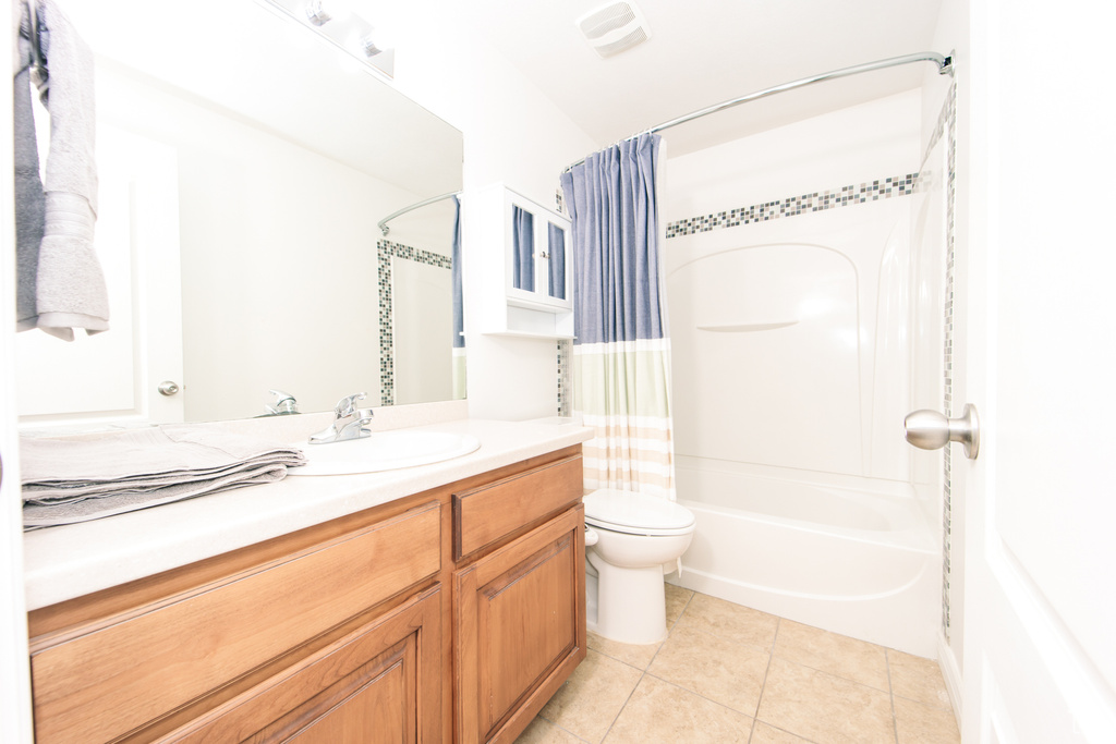 Full bathroom with tile floors, oversized vanity, shower / bath combo, and toilet