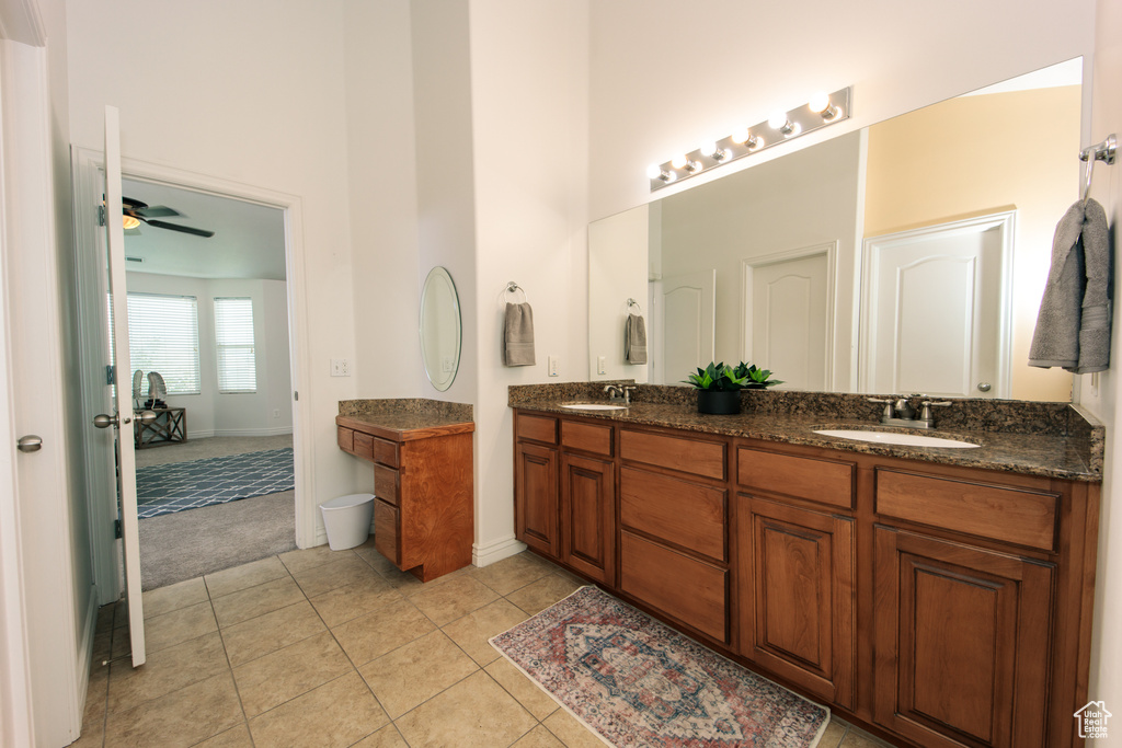 Bathroom with tile flooring, ceiling fan, vanity with extensive cabinet space, and double sink