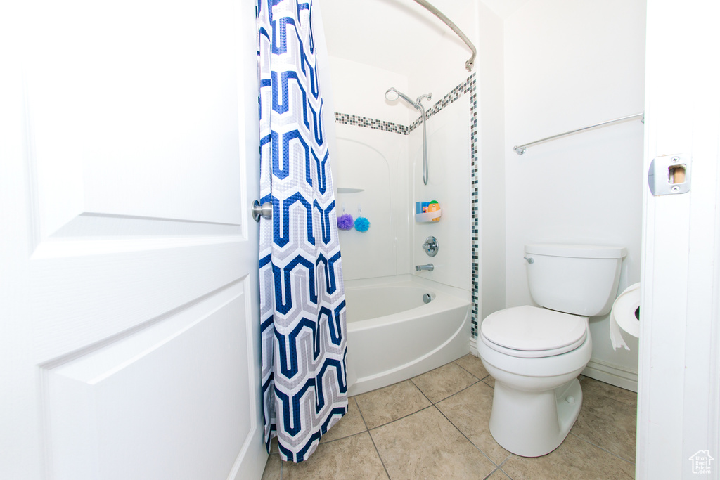 Bathroom with tile floors, toilet, and shower / bath combo with shower curtain