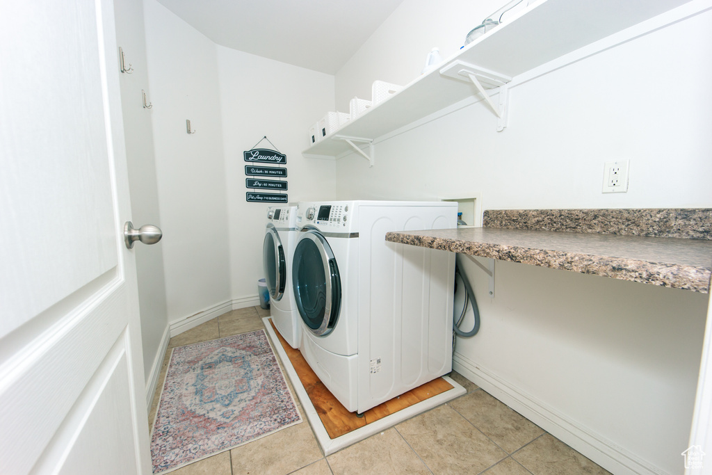 Clothes washing area featuring washing machine and dryer and light tile floors