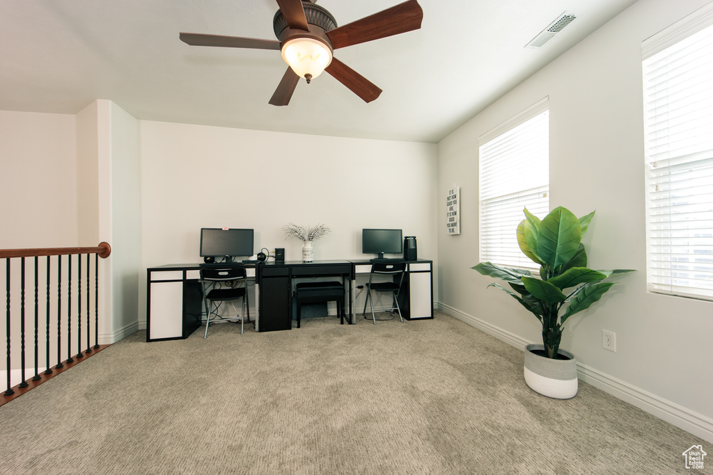Carpeted office featuring a healthy amount of sunlight and ceiling fan