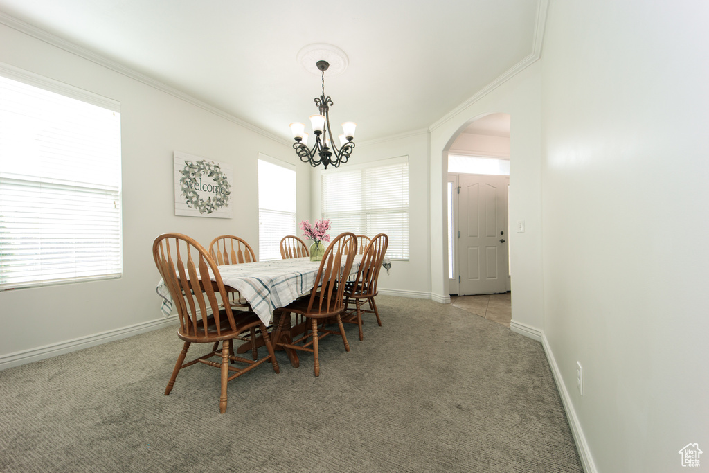 Dining area featuring light colored carpet, a chandelier, and crown molding