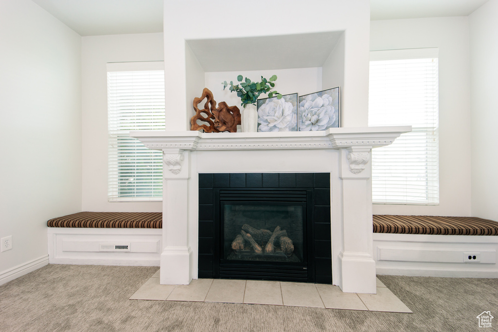Details featuring a tiled fireplace and light carpet