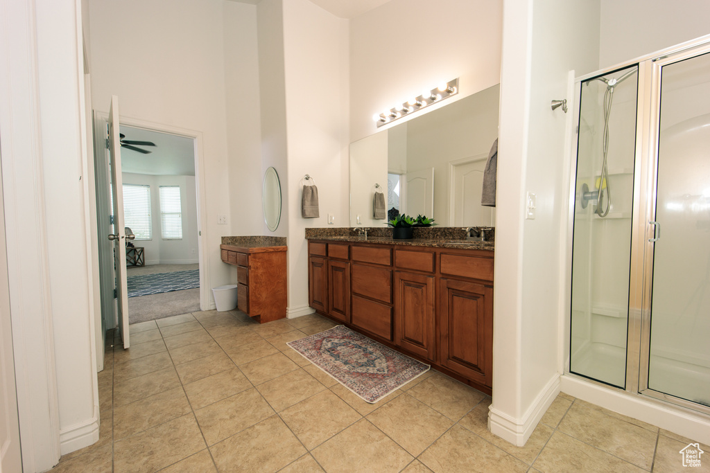 Bathroom with a shower with shower door, tile flooring, ceiling fan, and double sink vanity