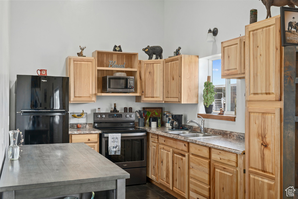 Kitchen with sink, light brown cabinets, and black appliances