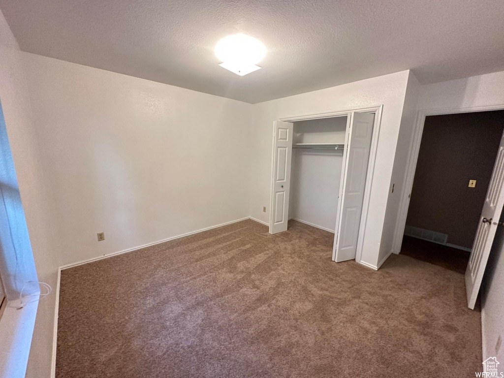 Unfurnished bedroom with a closet, carpet floors, and a textured ceiling
