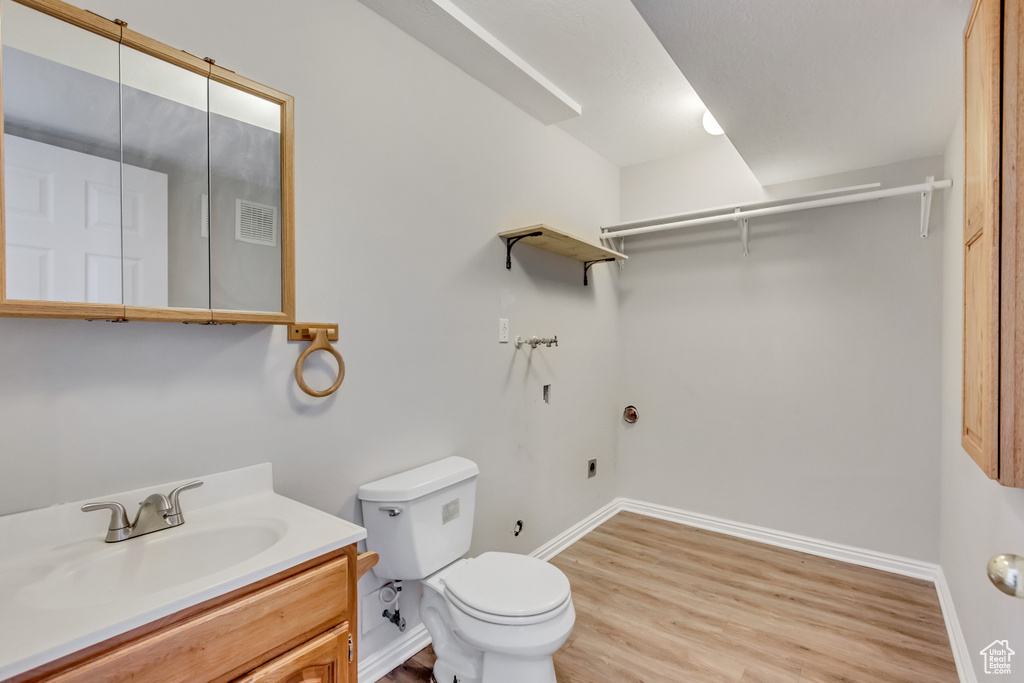 Bathroom featuring wood-type flooring, vanity with extensive cabinet space, and toilet