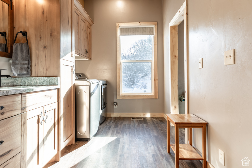Laundry room with wood-type flooring, cabinets, a healthy amount of sunlight, and washing machine and clothes dryer