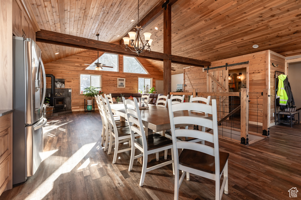 Dining space with hardwood / wood-style flooring, wood walls, a barn door, and vaulted ceiling with beams
