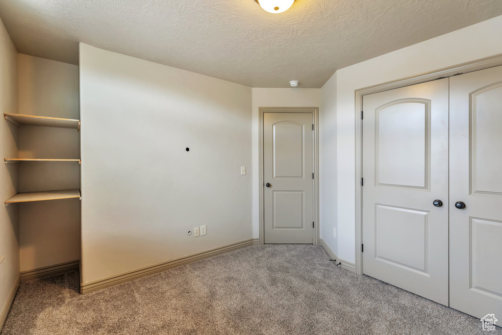 Unfurnished bedroom with carpet flooring, a closet, and a textured ceiling