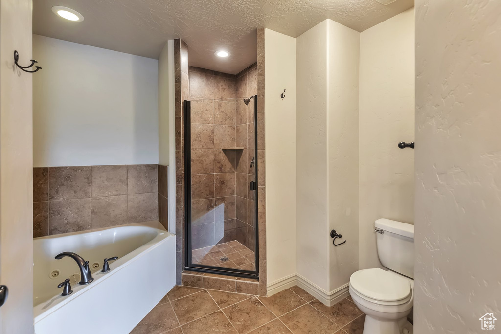 Bathroom featuring a textured ceiling, independent shower and bath, toilet, and tile flooring