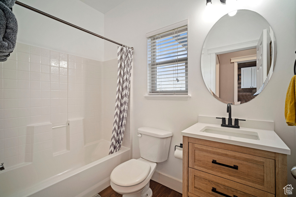 Full bathroom with hardwood / wood-style floors, vanity, shower / bathtub combination with curtain, and toilet