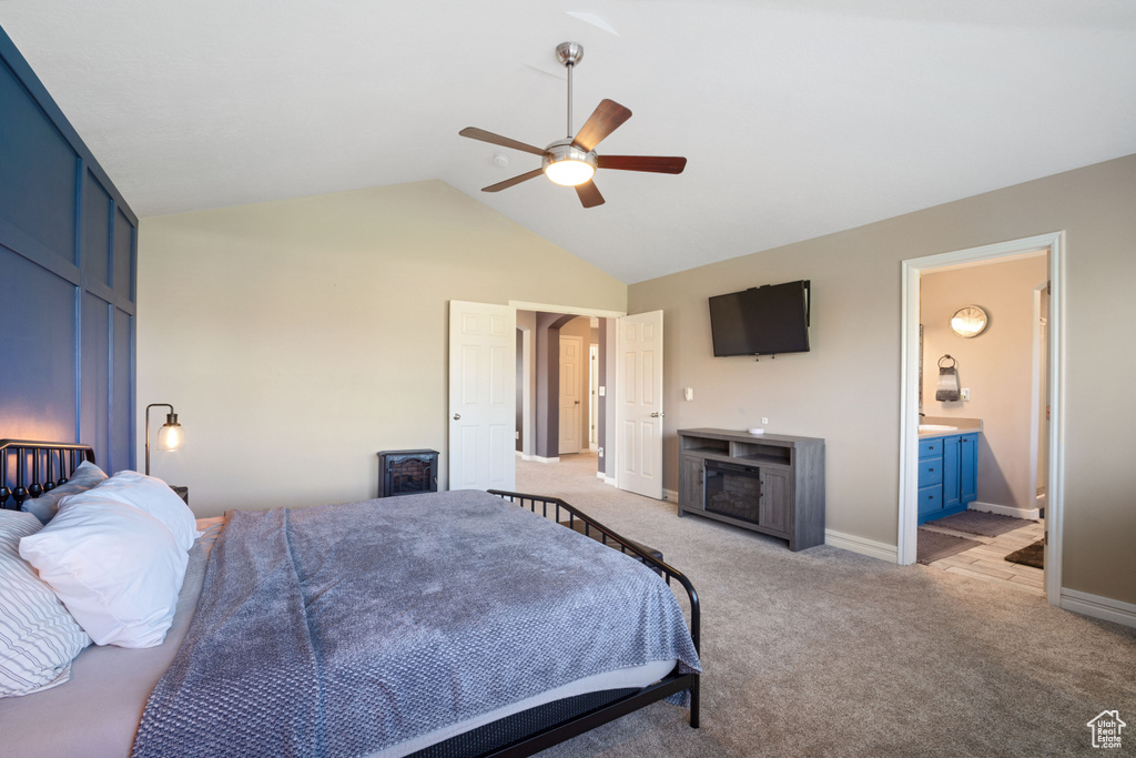 Bedroom with high vaulted ceiling, carpet floors, ceiling fan, and connected bathroom