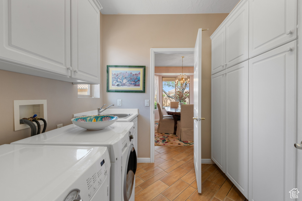 Laundry room with a healthy amount of sunlight, cabinets, a chandelier, and washer and clothes dryer