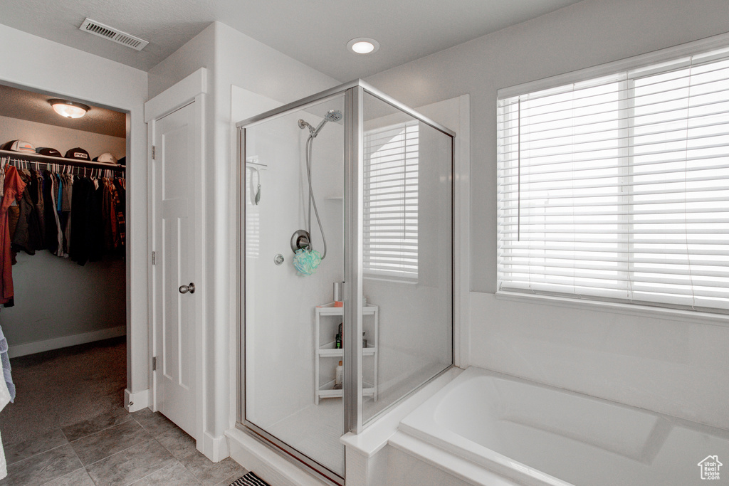 Bathroom with tile flooring, separate shower and tub, and a wealth of natural light