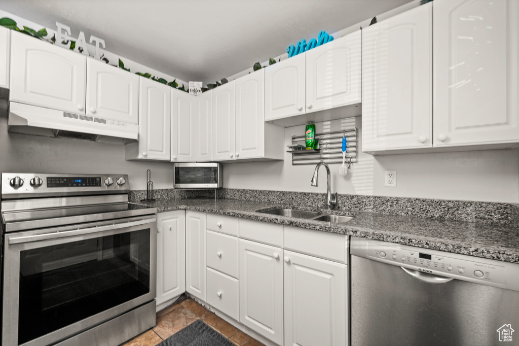 Kitchen featuring stainless steel appliances, white cabinetry, sink, and tile flooring