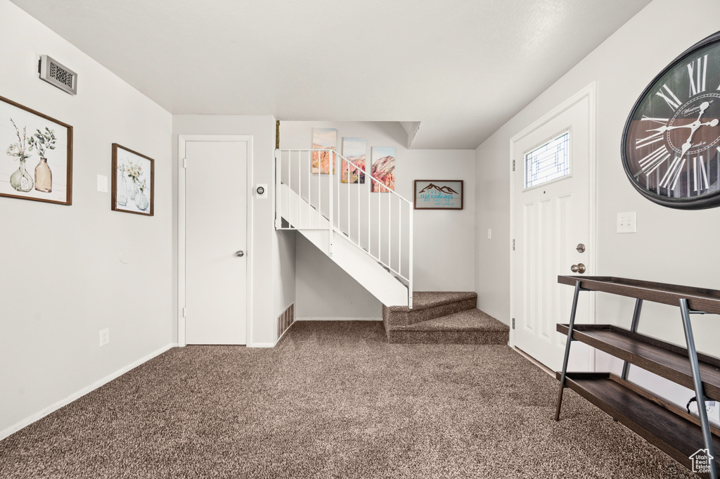 Foyer entrance featuring dark colored carpet