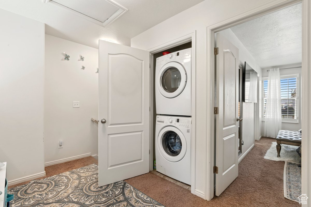 Laundry room with stacked washing maching and dryer and carpet floors