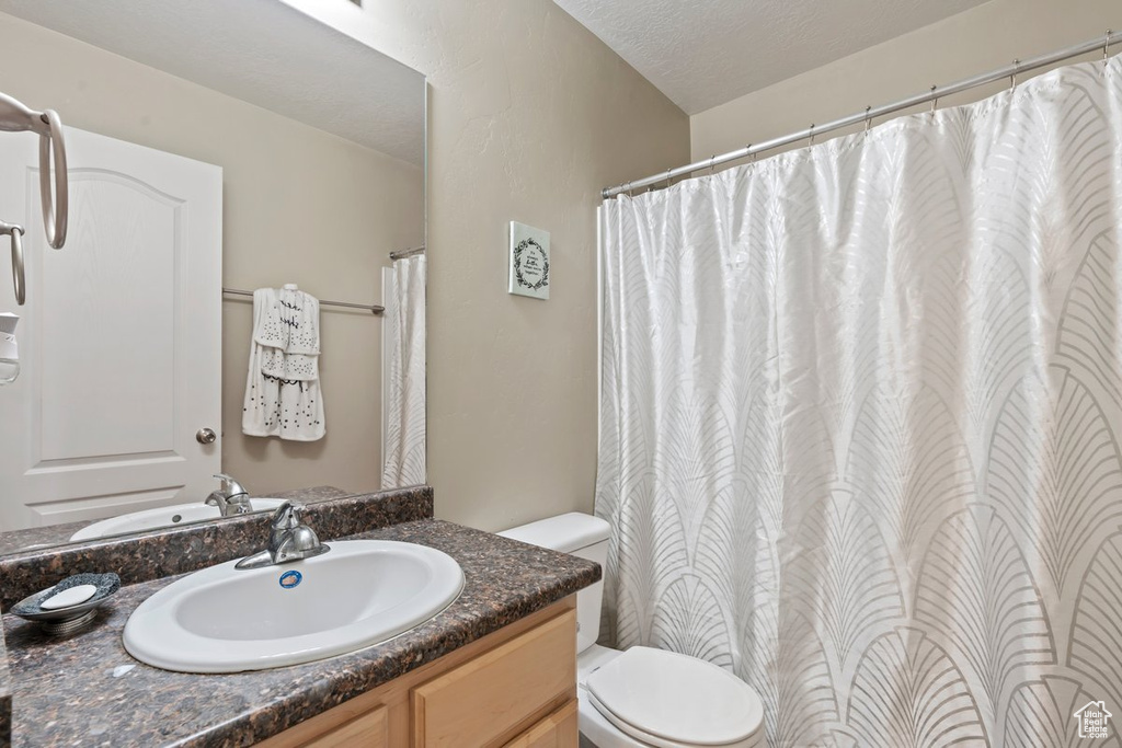 Bathroom featuring toilet, oversized vanity, and a textured ceiling