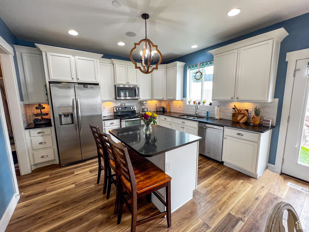 Kitchen featuring hardwood / wood-style floors, appliances with stainless steel finishes, a healthy amount of sunlight, and backsplash