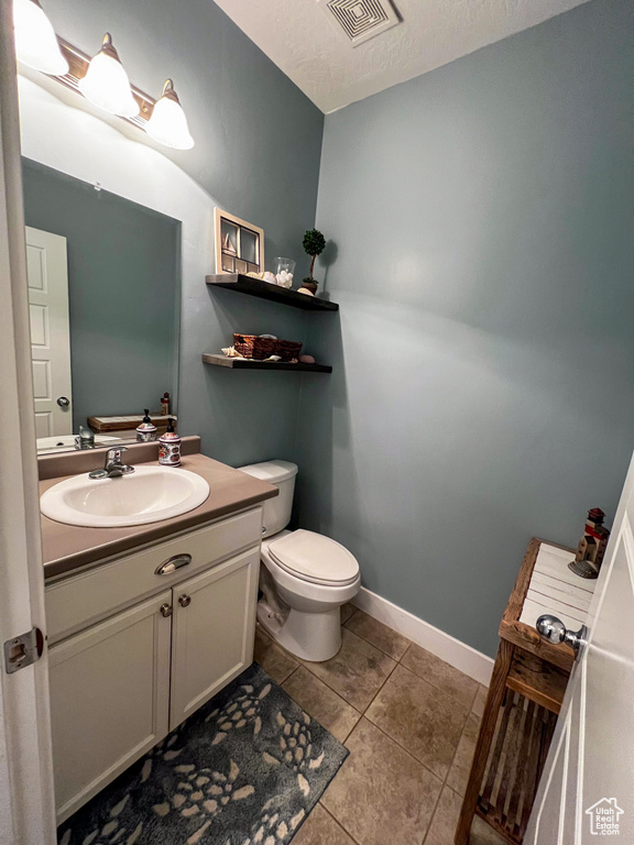 Bathroom with tile floors, vanity, toilet, and a textured ceiling