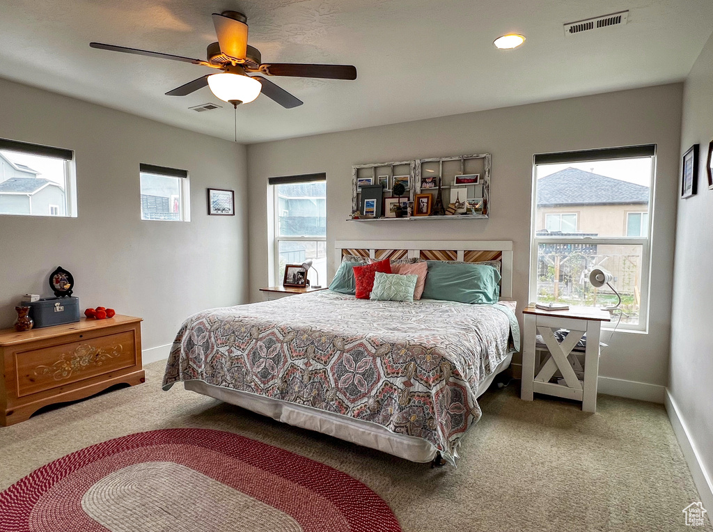 Bedroom featuring carpet floors, ceiling fan, and multiple windows