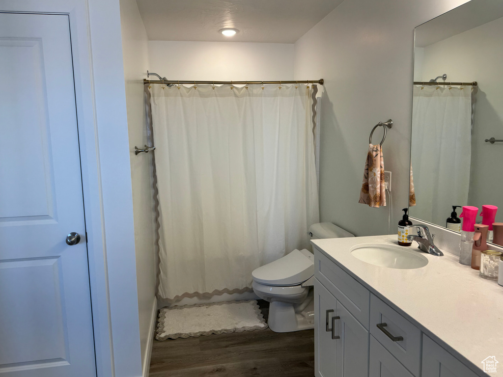 Bathroom with hardwood / wood-style flooring, toilet, and oversized vanity